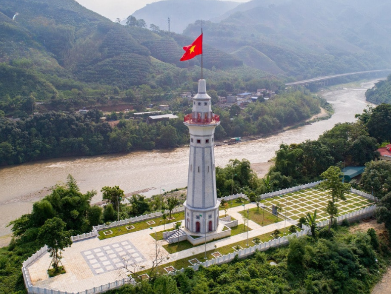 Hình ảnh lá cờ Tổ quốc tung bay trên đỉnh cột, soi bóng xuống sông.